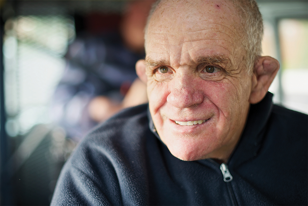 Older man with a disability, smiling.