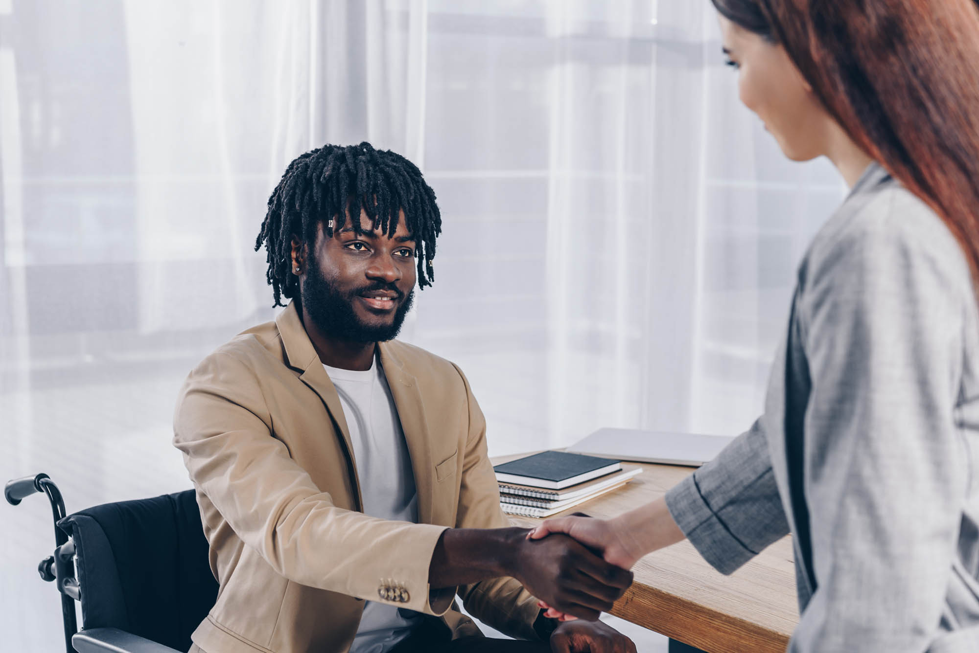 A Black man with a disability shaking the hand of a DSW candidate.