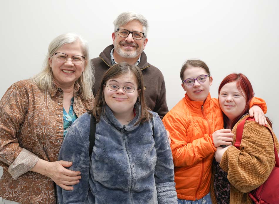 En un retrato de familia aparecen dos padres con gafas y tres mujeres jóvenes adultas.