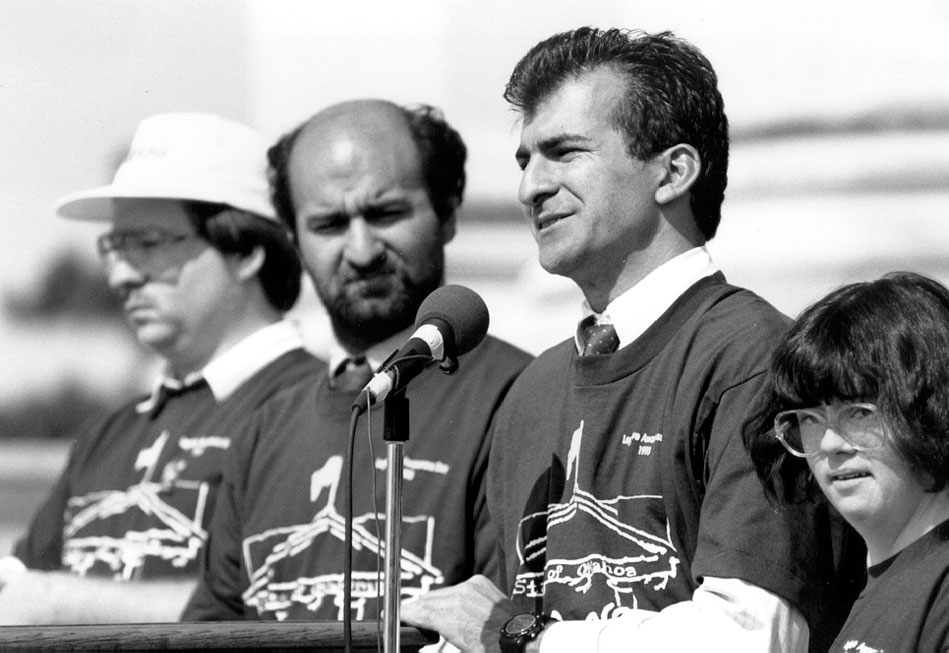 Four people stand near a microphone.