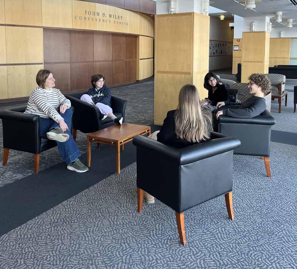 Un grupo de estudiantes se reúne en un círculo de sillas tapizadas.