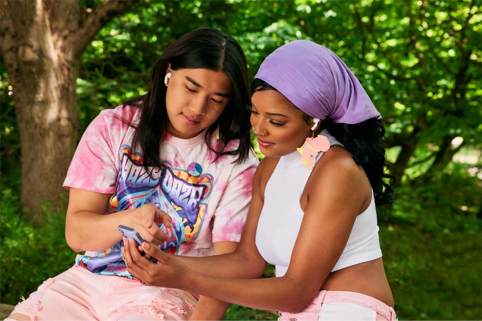 Two people sit close together, looking at a phone.