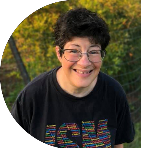 A woman with short, dark hair and glasses smiles, looking ahead.