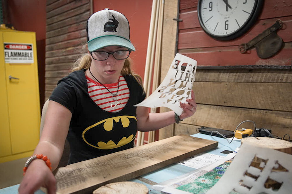 A worker with a disability works in a stenciling job at a factory.