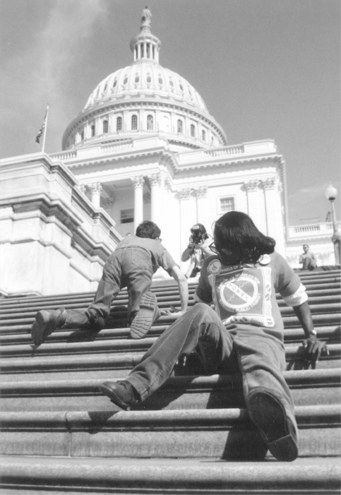 Dos personas con discapacidades físicas suben a gatas los escalones del Capitolio de los Estados Unidos durante una protesta por los derechos de las personas con discapacidades.