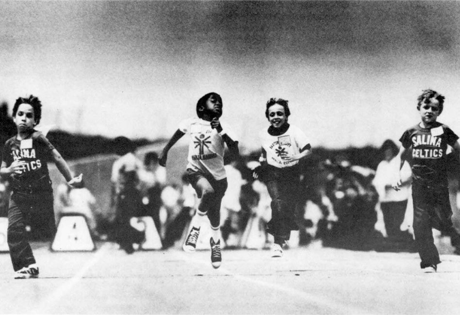 Para corredores esprintando, con espectadores al fondo.