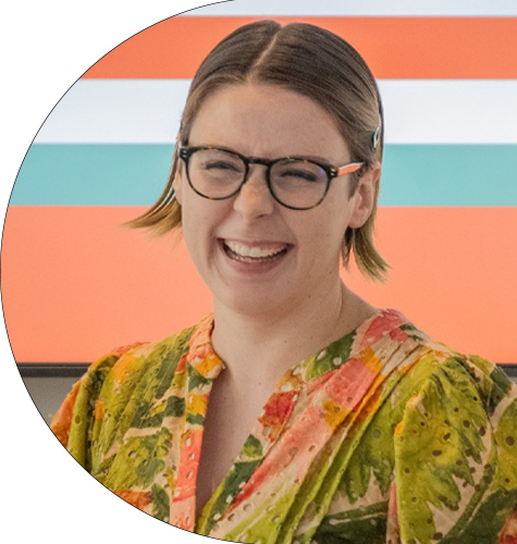 A smiling woman wearing glasses, over an orange, blue, and white-striped background.