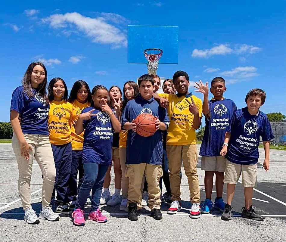 young woman standing with a children's basketball team, outside