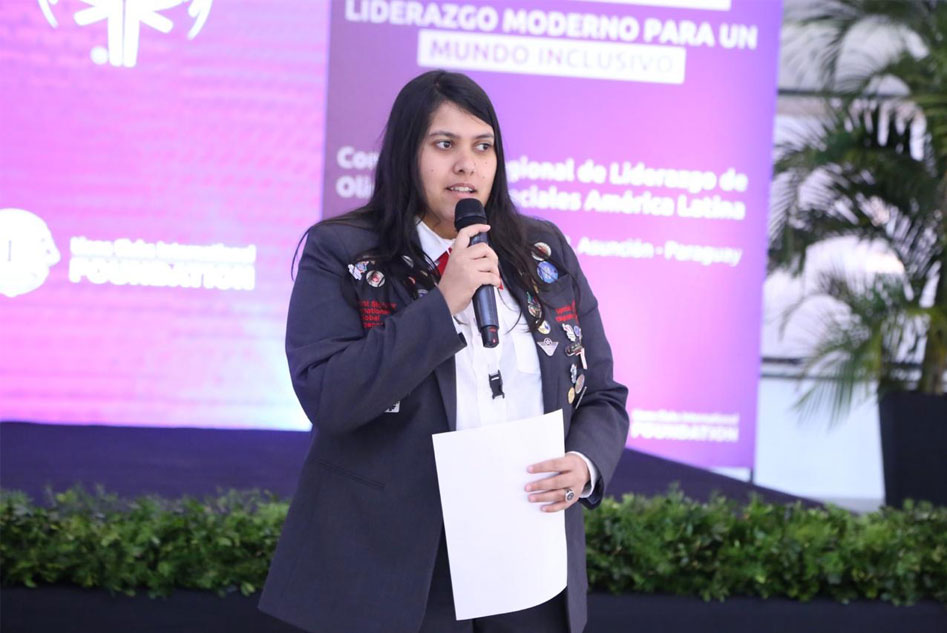 persona in decorated blazer holding a mic and paper
