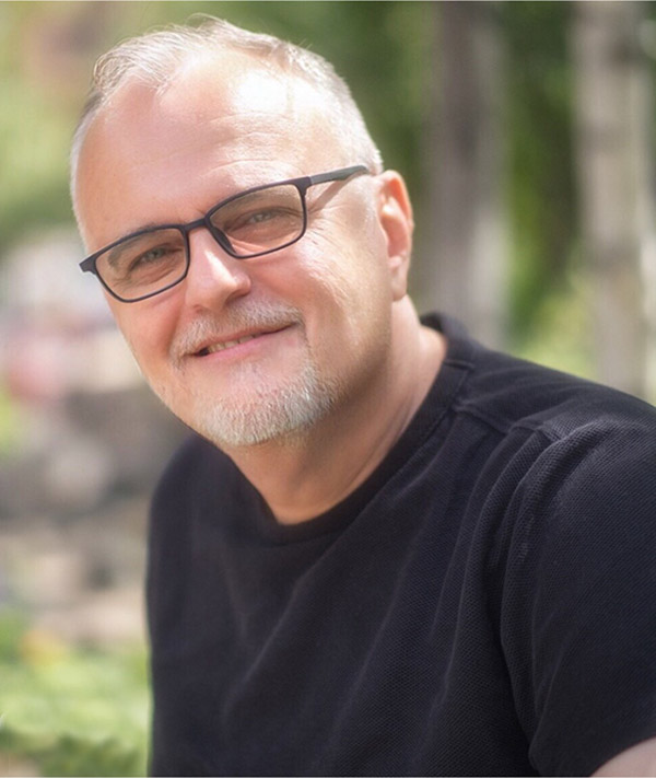 Bearded white man wearing glasses and a black shirt.