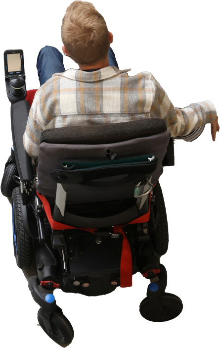Una persona con el cabello corto y claro está sentada sola en una silla de ruedas, de espaldas a la cámara, y lleva una camisa a cuadros.